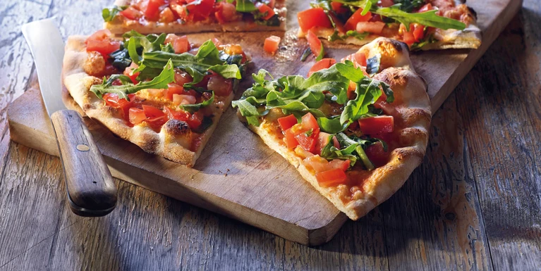 Pizza Pane mit Tomaten & Rucola, in St√ºcke geschnitten auf Holzbrett