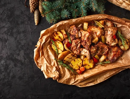 Dish for Christmas, baked rabbit meat with vegetables close-up on baking paper on the table.