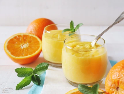 Orange curd and juicy oranges in two glasses