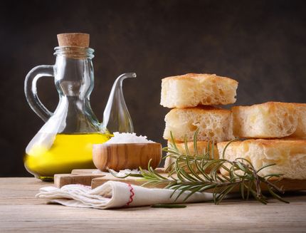 Genoese focaccia, extra virgin olive oil, salt and fresh rosemary on wooden table, close-up, space for text.