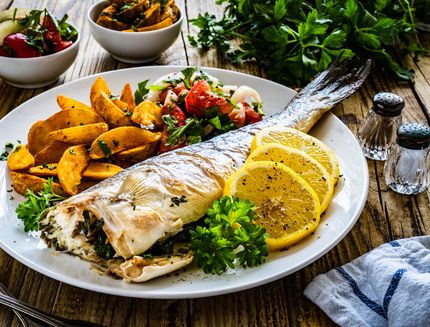 Fish dish – roasted sea bream with vegetables on wooden table